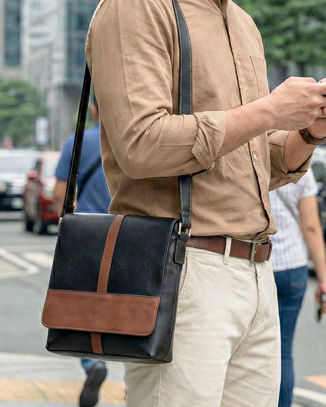 Man carrying a black and brown leather bag on a city street