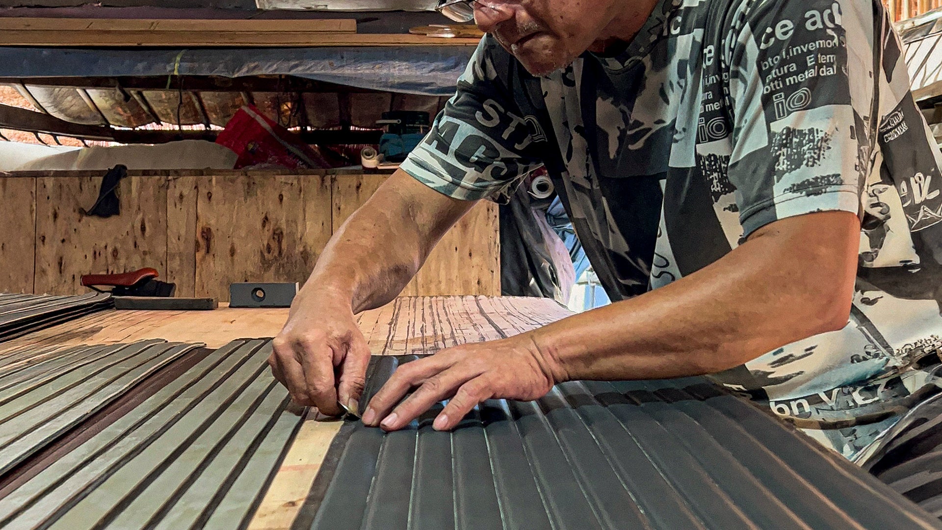 Person working on a wooden surface with tools in a workshop creating a leather betls